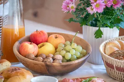 a wooden bowl of apples and grapes on a table at Turnerhof in Bressanone