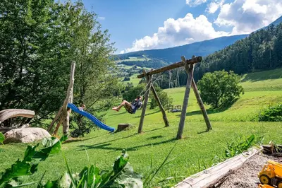 a group of people playing on a swing set in a field at Turnerhof in Bressanone