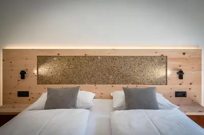 a bedroom with two white beds and a wooden wall at Turnerhof in Bressanone