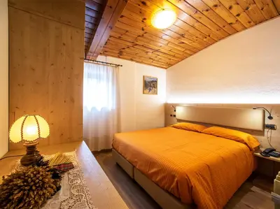 a bedroom with a bed and a lamp on a table at Hotel Adriana in Alleghe