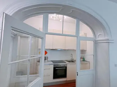 an arched doorway to a kitchen with white cabinets at Atelier La Stube - Alpine Design Home in Bolzano