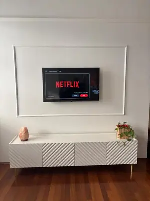 a tv mounted on a white wall in a living room at Atelier La Stube - Alpine Design Home in Bolzano