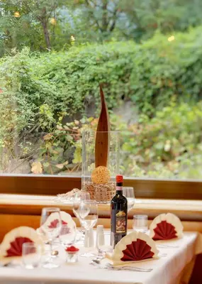 a table with a bottle of wine and wine glasses at Hotel Laurin in Lagundo