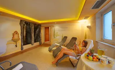 a woman sitting in a chair in a room at Hotel Laurin in Lagundo