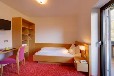 a bedroom with a bed and a desk and a chair at Hotel Laurin in Lagundo