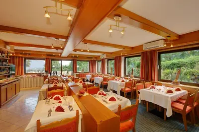 a restaurant with white tables and chairs and windows at Hotel Laurin in Lagundo
