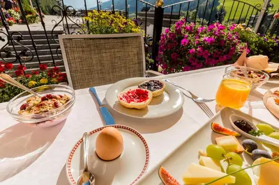 a table with a plate of breakfast foods and orange juice at Hotel Rosenheim in Racines