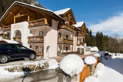 a car parked in front of a house in the snow at Hotel Rosenheim in Racines