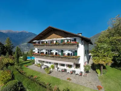 a large white building with a balcony with flowers at Garni Pluner in Schenna