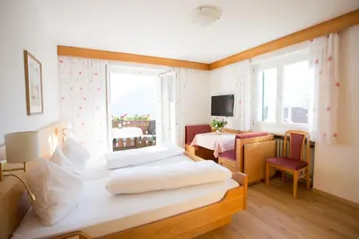 a hotel room with two beds and a window at Garni Pluner in Schenna