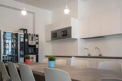 a kitchen with a wooden table and white chairs at Stay COOPER l Capitol Rooms in Bolzano