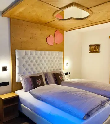 a bedroom with two beds with blue sheets at Hotel Genziana in Arabba
