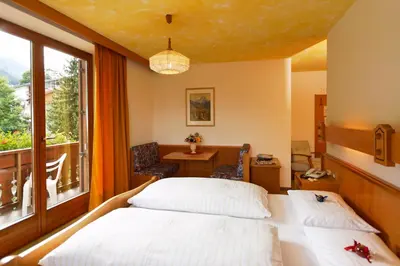 a bedroom with a bed and a table and a window at Hotel Genziana in Arabba