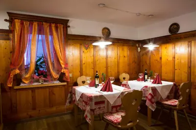 a dining room with two tables and chairs and a window at Hotel Genziana in Arabba