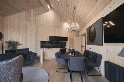 a dining room with a table and blue chairs at Tenne Lodges in Racines
