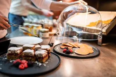 a table topped with plates of desserts and a cake at Romantik Hotel & Restaurant Stafler in Vipiteno
