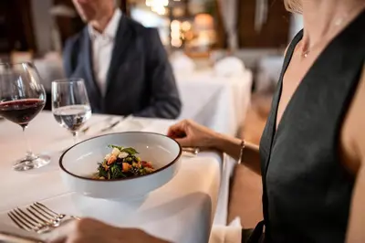 a woman sitting at a table with a bowl of food at Romantik Hotel & Restaurant Stafler in Vipiteno