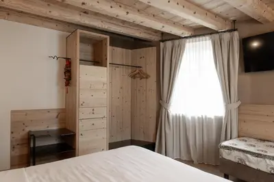 a living room with two beds and a table at Hotel Orso Grigio in Cavalese