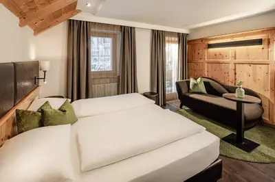 a hotel room with two beds and a couch at Boutique & Fashion Hotel Maciaconi - Gardenahotels in Santa Cristina in Val Gardena