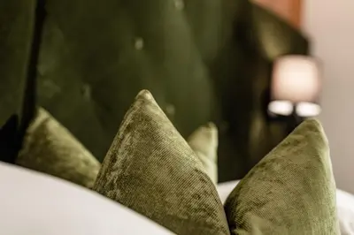 a pile of green pillows on a bed at Boutique & Fashion Hotel Maciaconi - Gardenahotels in Santa Cristina in Val Gardena