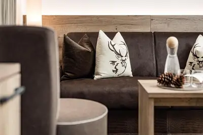 a living room with a couch with pillows and a table at Boutique & Fashion Hotel Maciaconi - Gardenahotels in Santa Cristina in Val Gardena