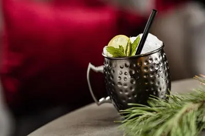 a metal cup with a cocktail on a table at Boutique & Fashion Hotel Maciaconi - Gardenahotels in Santa Cristina in Val Gardena