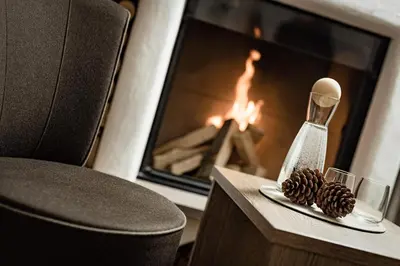 a room with a fireplace and a table with pine cones at Boutique & Fashion Hotel Maciaconi - Gardenahotels in Santa Cristina in Val Gardena
