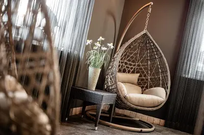 a swing chair in a room with a vase of flowers at Boutique & Fashion Hotel Maciaconi - Gardenahotels in Santa Cristina in Val Gardena