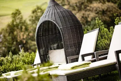 a bird cage sitting on top of a table with chairs at Boutique & Fashion Hotel Maciaconi - Gardenahotels in Santa Cristina in Val Gardena