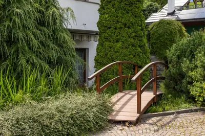 a wooden bridge over a walkway in a garden at B&B Villa Pattis in Vipiteno