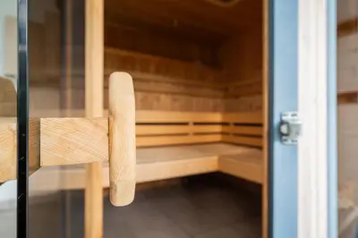 a wooden bench in a sauna with a glass door at B&B Villa Pattis in Vipiteno