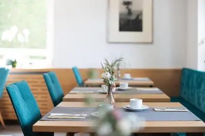 a row of tables in a restaurant with blue chairs at Garni Juval in Tirolo