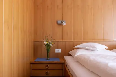 a bedroom with a bed and a vase of flowers on a table at Garni Juval in Tirolo
