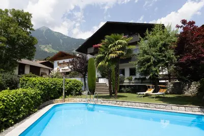 a villa with a swimming pool in front of a house at Garni Juval in Tirolo