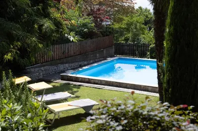 a swimming pool in a garden with two chairs and a table at Garni Juval in Tirolo