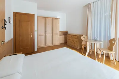 a bedroom with a bed and a table and chairs at Hotel Montana in Cortina dʼAmpezzo