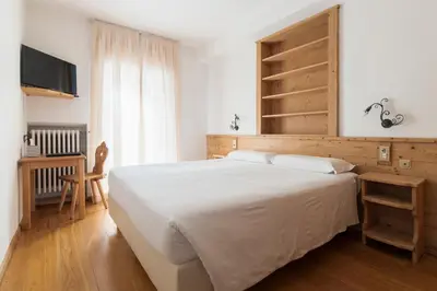 a bedroom with a large white bed and a television at Hotel Montana in Cortina dʼAmpezzo