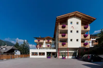 a building with flower baskets on the side of it at Hotel Mirabel in San Vigilio Di Marebbe