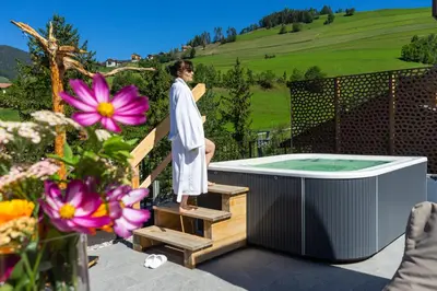 a man standing on the stairs next to a hot tub at Hotel Mirabel in San Vigilio Di Marebbe
