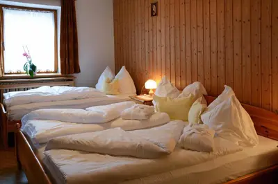 two beds in a room with white blankets and pillows at Hotel Mirabel in San Vigilio Di Marebbe