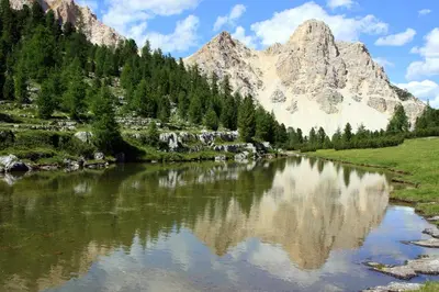 a mountain reflecting in a lake in the mountains at Hotel Mirabel in San Vigilio Di Marebbe