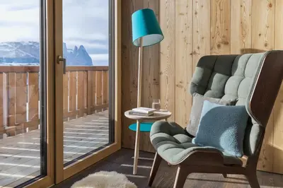 a room with a chair and a lamp and a balcony at ICARO Hotel in Alpe di Siusi