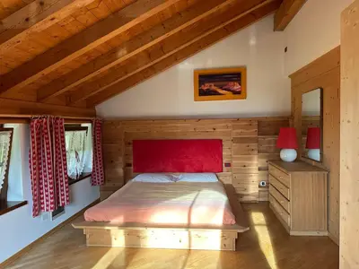 a bedroom with a bed with a red head board at Casa del Cirmolo - apartments for rent in Cavalese
