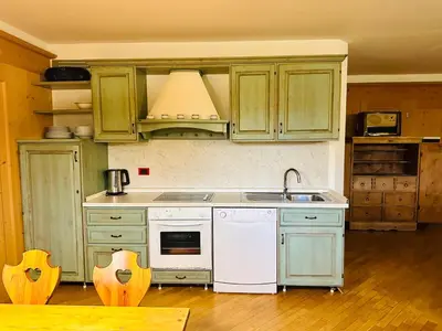 a kitchen with green cabinets and a white dishwasher at Casa del Cirmolo - apartments for rent in Cavalese