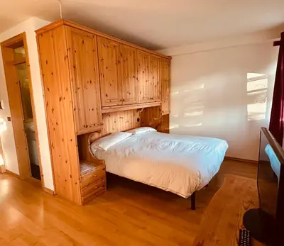 a bedroom with a bed and wooden cabinets at Casa del Cirmolo - apartments for rent in Cavalese