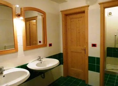a bathroom with two sinks and a wooden door at Casa del Cirmolo - apartments for rent in Cavalese