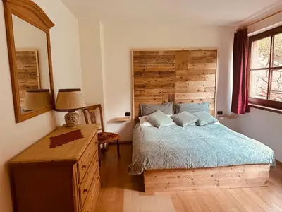 a bedroom with a bed and a wooden headboard at Casa del Cirmolo - apartments for rent in Cavalese