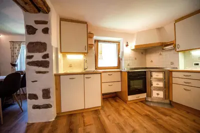 a kitchen with white cabinets and a wooden floor at Apartments Smidl in Ortisei