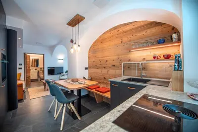 a kitchen with a table and a wooden wall at Apartments Smidl in Ortisei