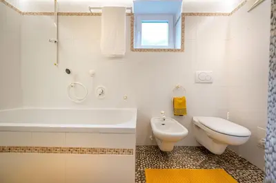 a bathroom with a tub and a toilet and a sink at Apartments Smidl in Ortisei